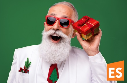 Moderner Weihnachtsmann mit Sonnenbrille und einem kleinen Geschenk in der Hand